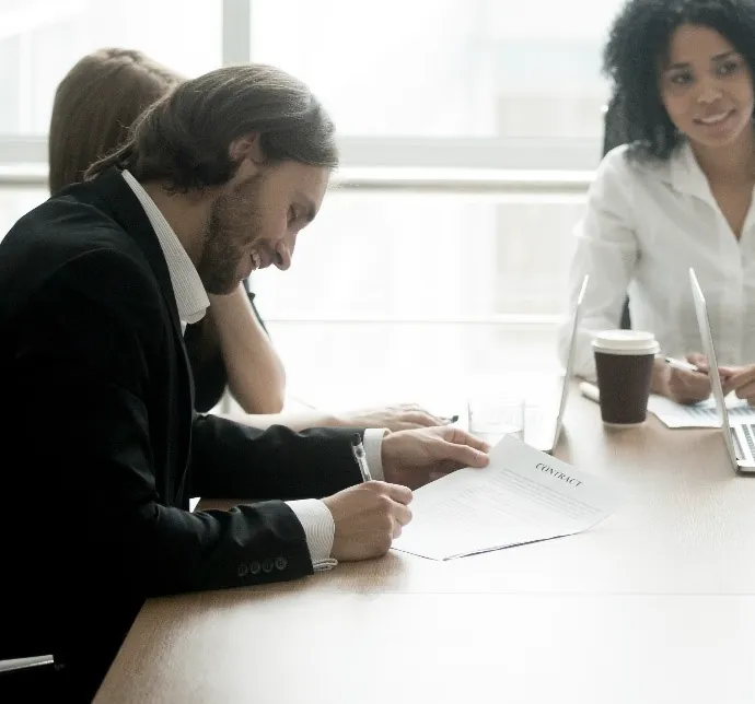 A client signing a contract at a meeting table