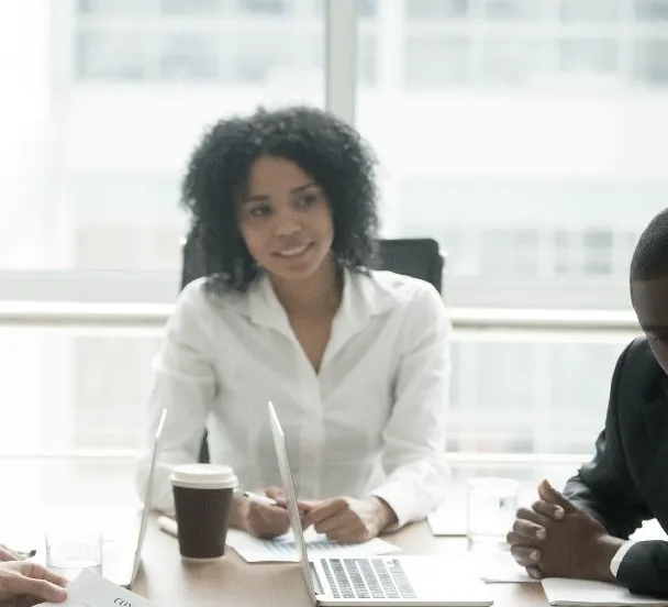 A smiling solicitor at a meeting table with colleagues