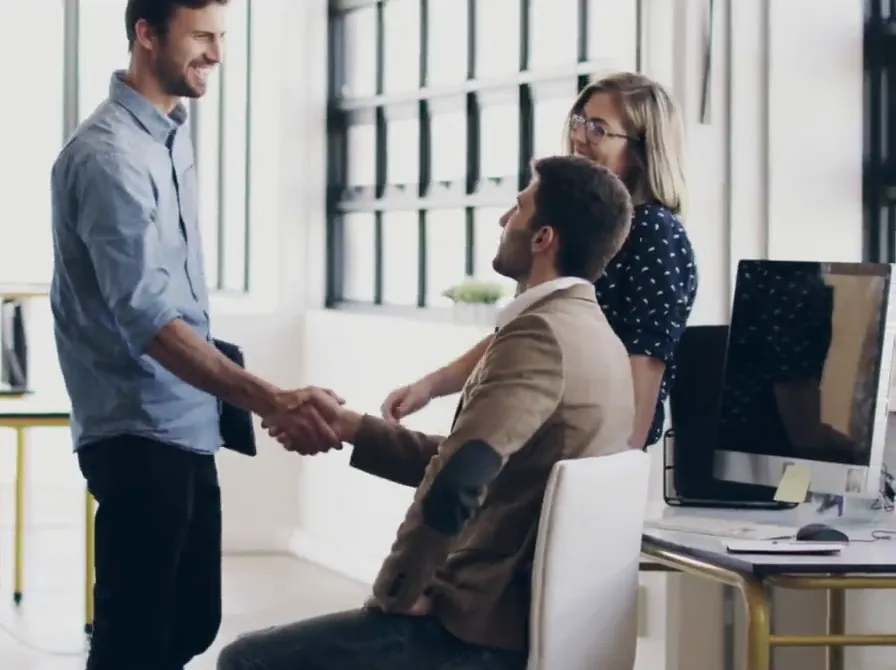 Colleagues greeting each other with a handshake in a bright office